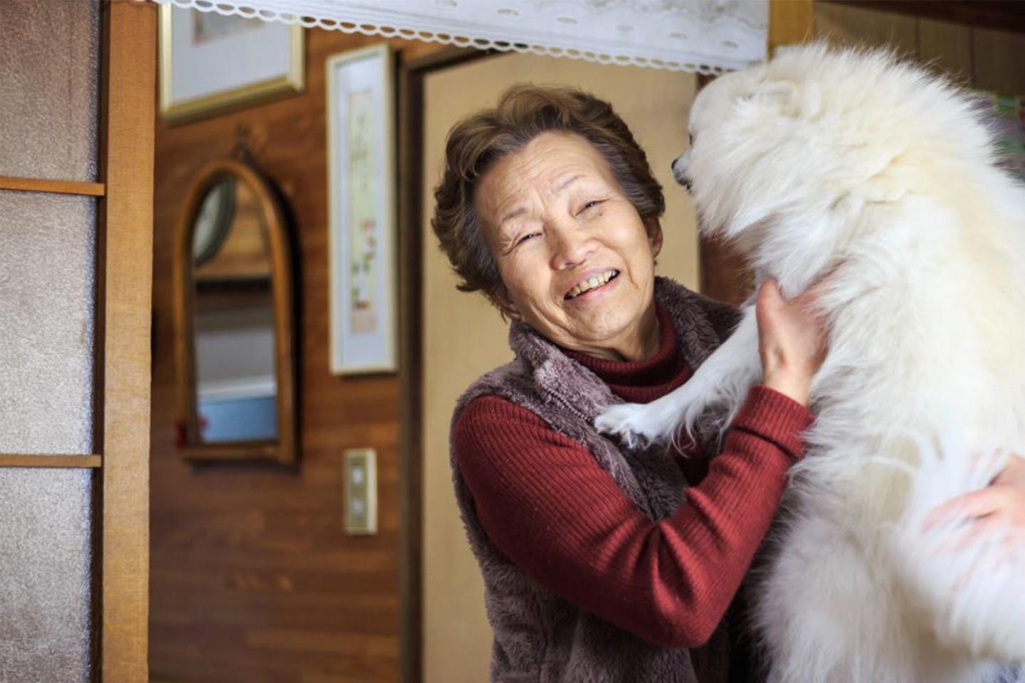 Photo of a smiling woman and a fluffy cream dog
