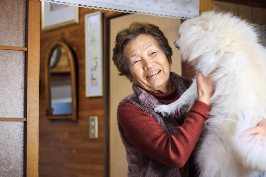 Photo of a smiling woman and a fluffy cream dog