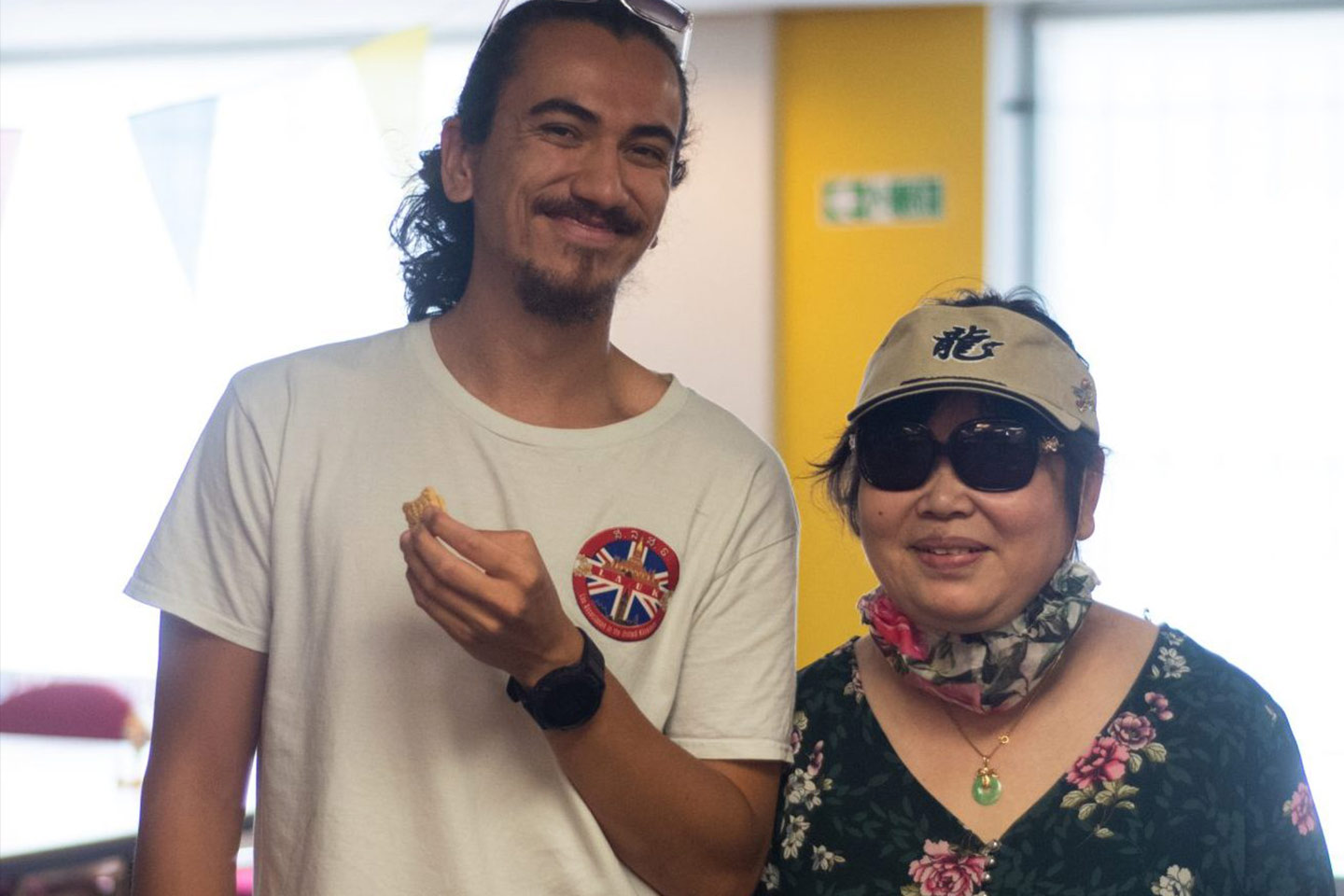 Photo of man in a white t-shirt and woman with cap and sunglasses