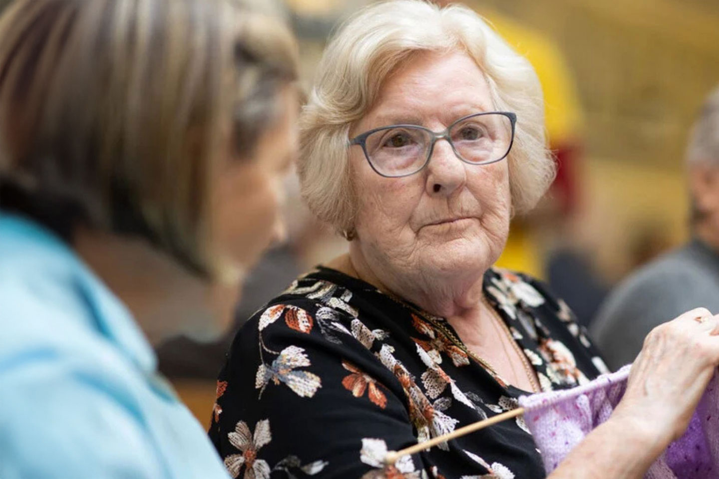 Photo of a woman wearing glasses and knitting