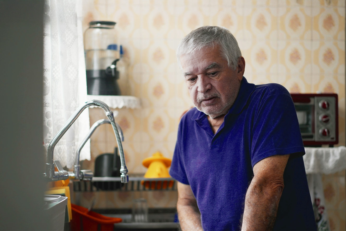 Photo of a man in a royal blue polo standing in his kitchen