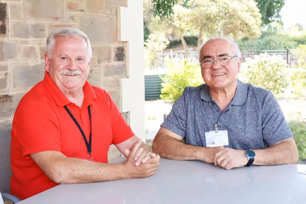 Photo of two smiling men sitting at a table