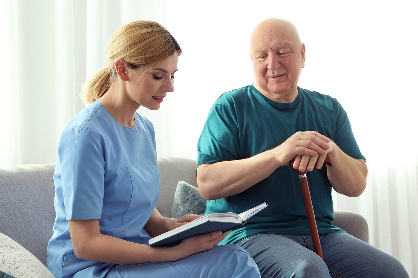 Photo of health professional reading a book next to an older man