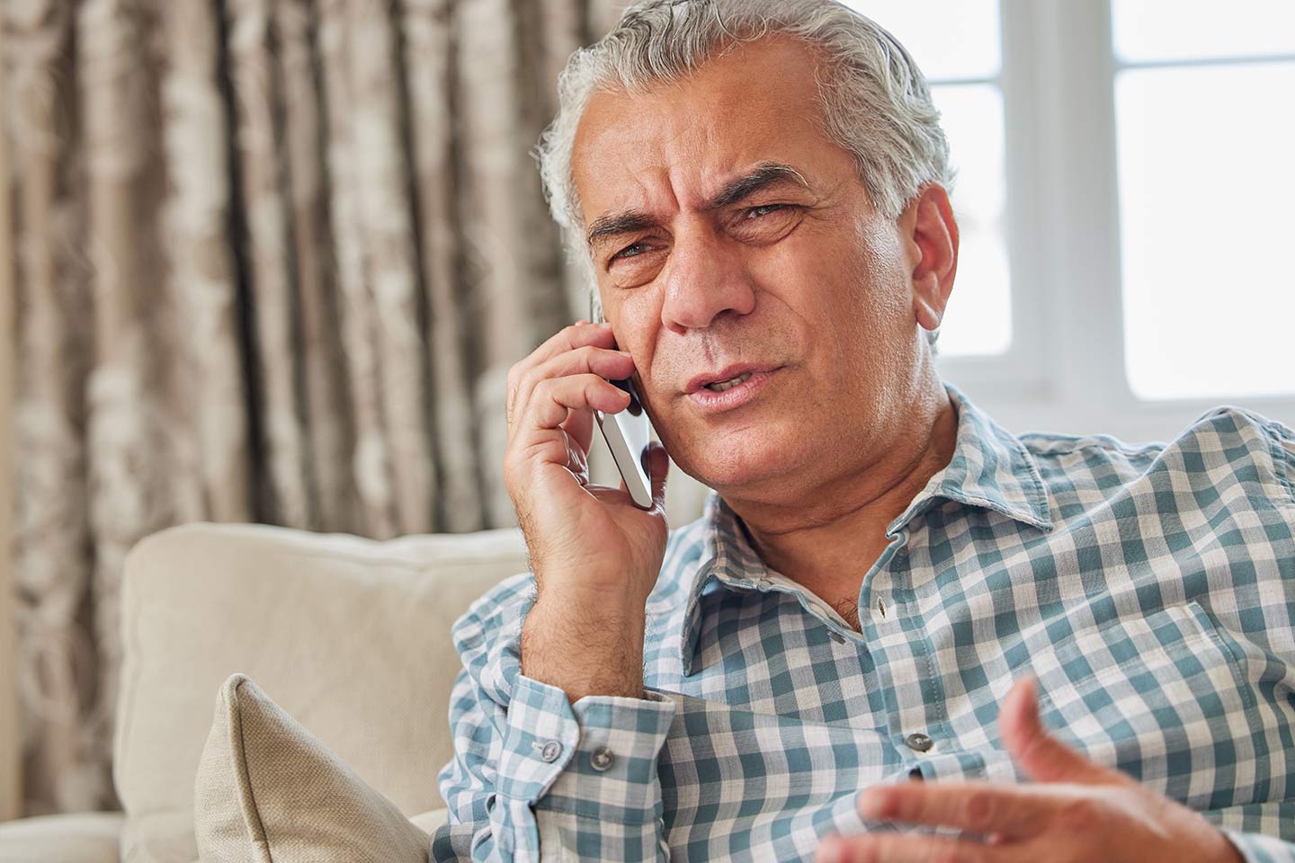 Photo of man in a teal check shirt using a mobile phone