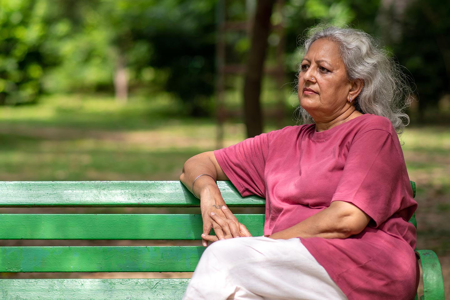 Photo of a woman in a red t shirt sitting on a park bench