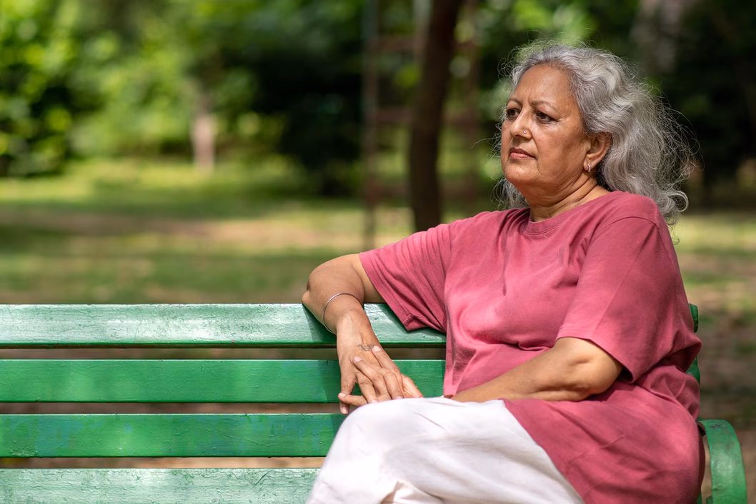 Photo of a woman in a red t shirt sitting on a park bench