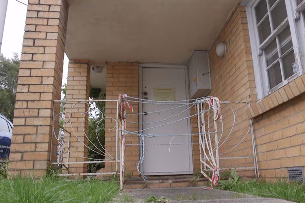 Photo of gate in front of a condemned building