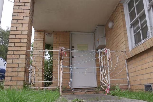 Photo of gate in front of a condemned building