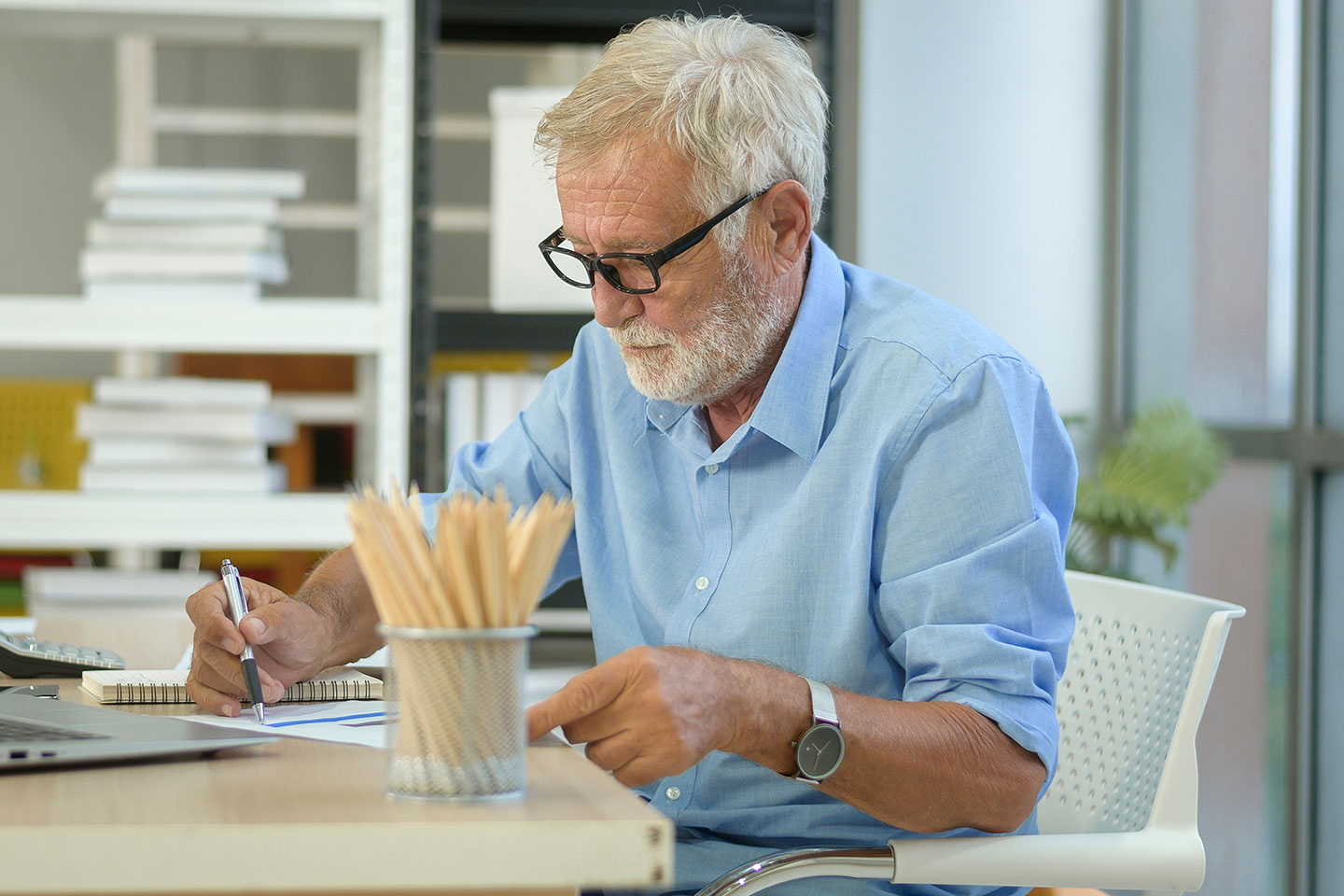 Photo of bearded senior working in office