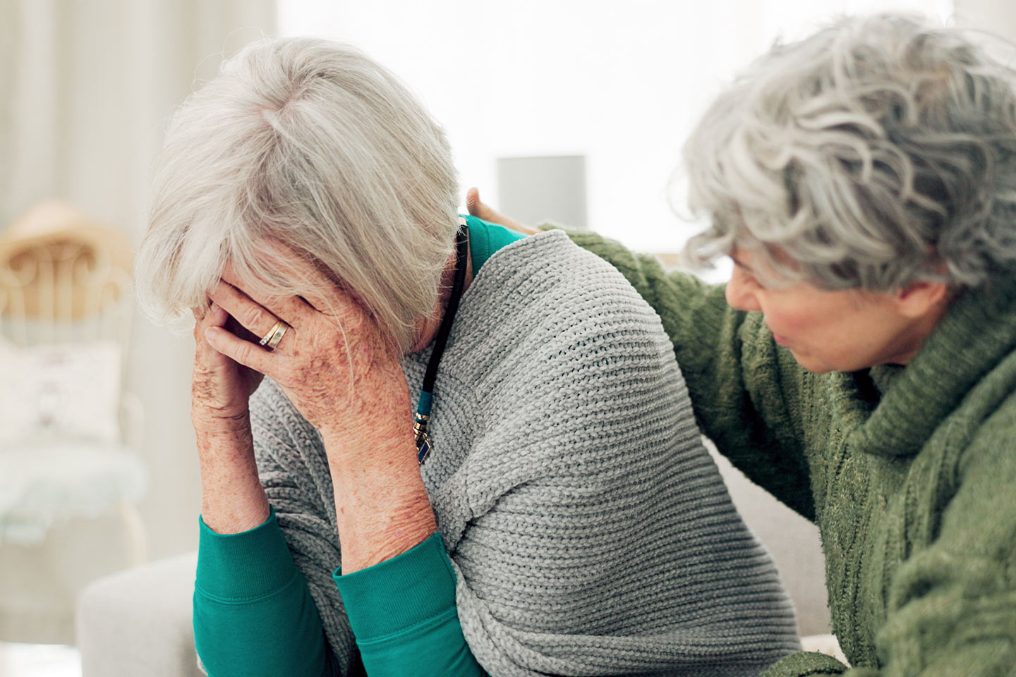 Photo of woman in a green jumper comforting another woman