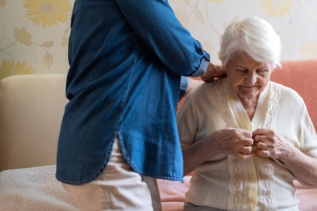 Photo of woman getting dressed with help from another person