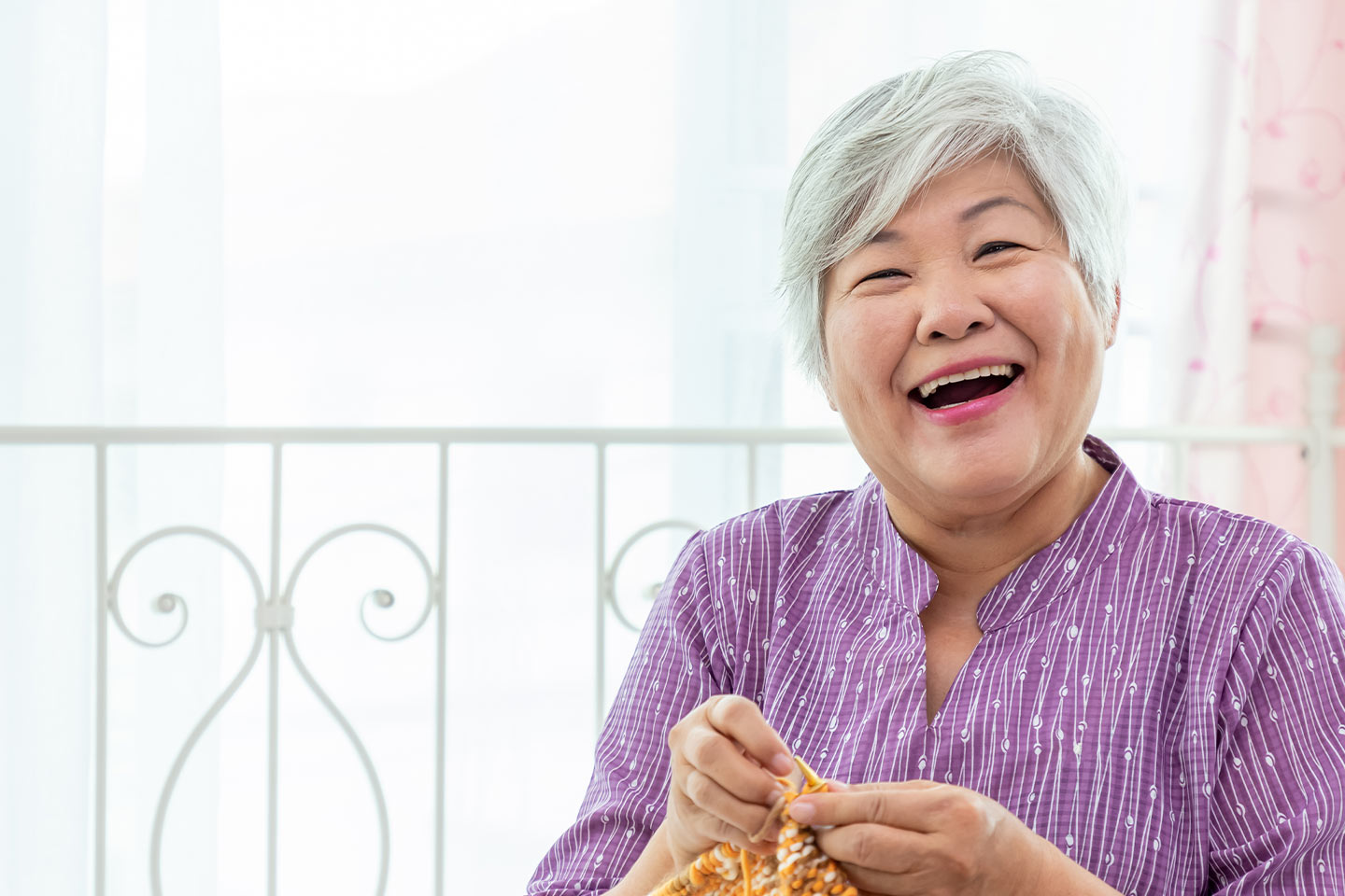 Photo of happy lady in a purple shirt knitting