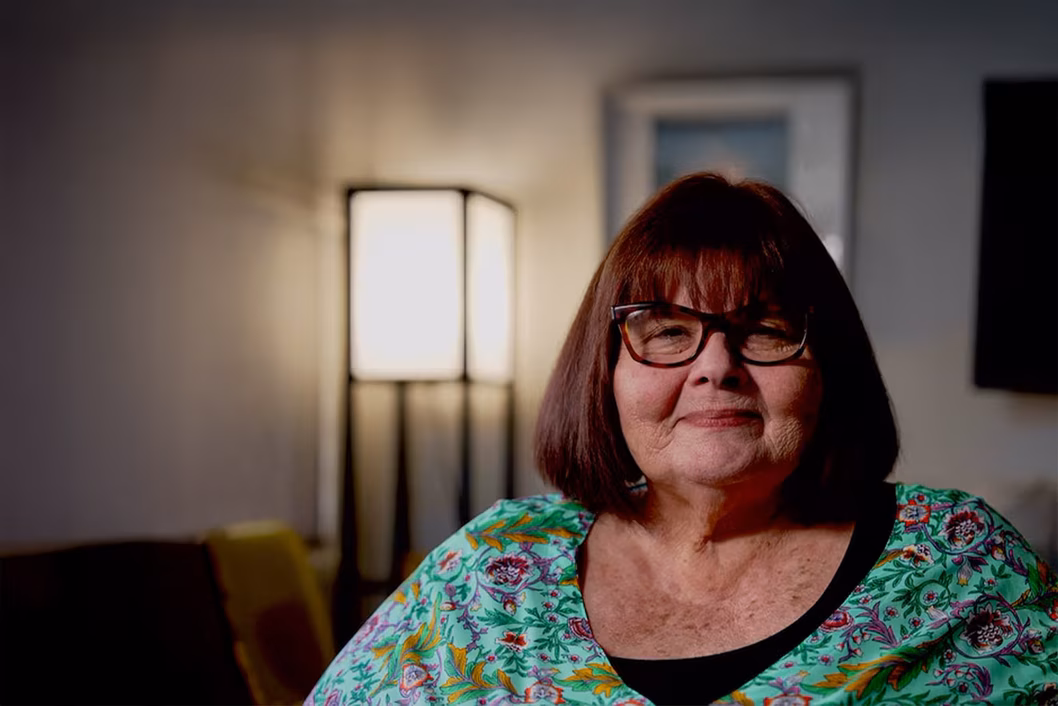 Photo of a woman in a paisley teal top in a cosy room