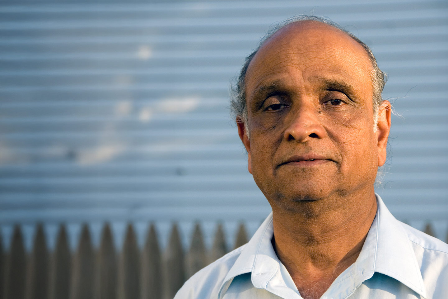 Photo of a man standing in front of a picket fence