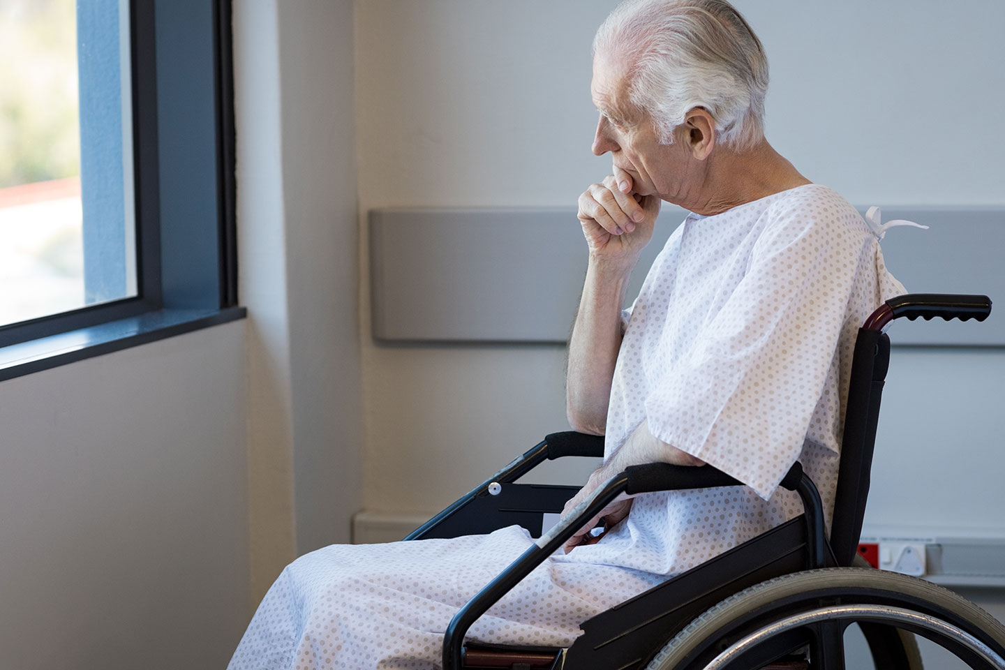 Photo of a man in a hospital gown in wheelchair