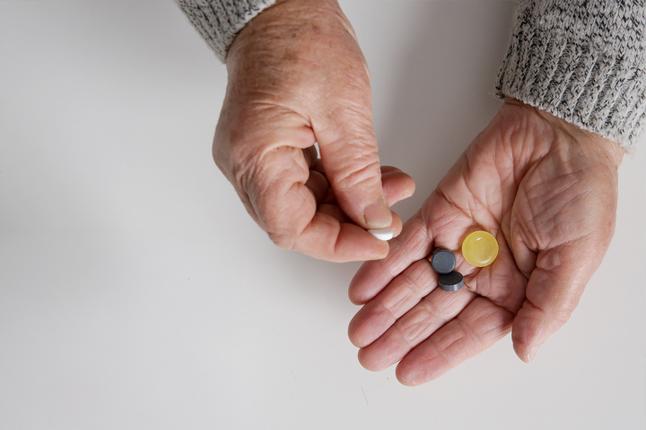 Photo of two hands holding a selection of pills