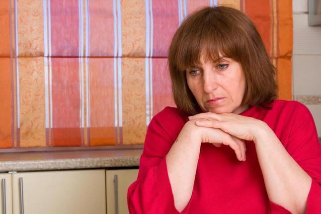 Photo of a woman in a red top looking downcast