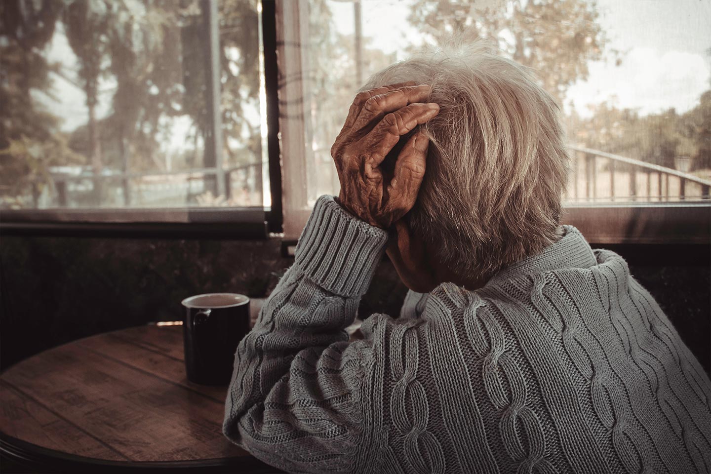 Photo of a seated woman with a cuppa looking outside