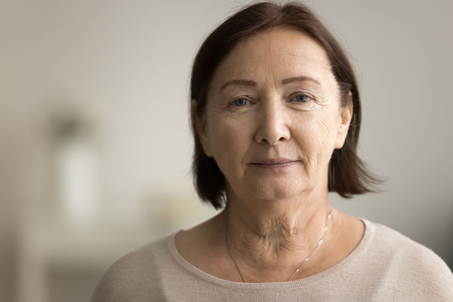 Photo of a woman with a brown bob and wearing a cream knit