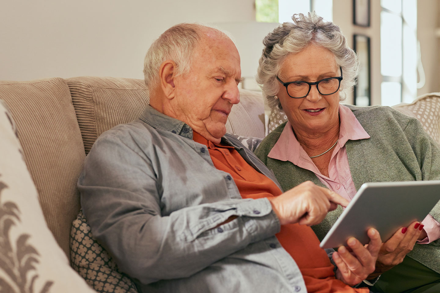 Photo of a couple sitting on a couch with a tablet
