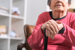 Image of an older woman's hands resting on a walking stick