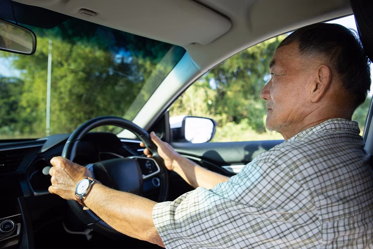 Image of an older Asian man driving a car