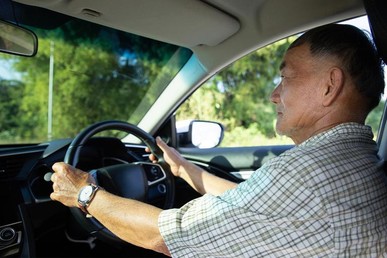 Image of an older Asian man driving a car