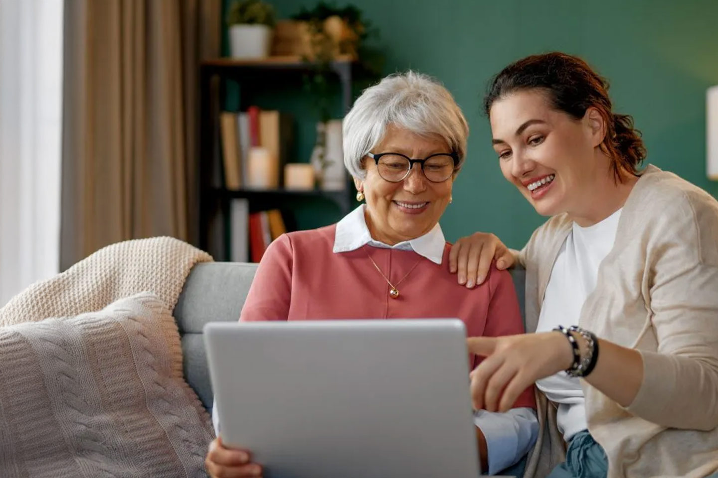 Photo of two women smiling as they look at a laptop