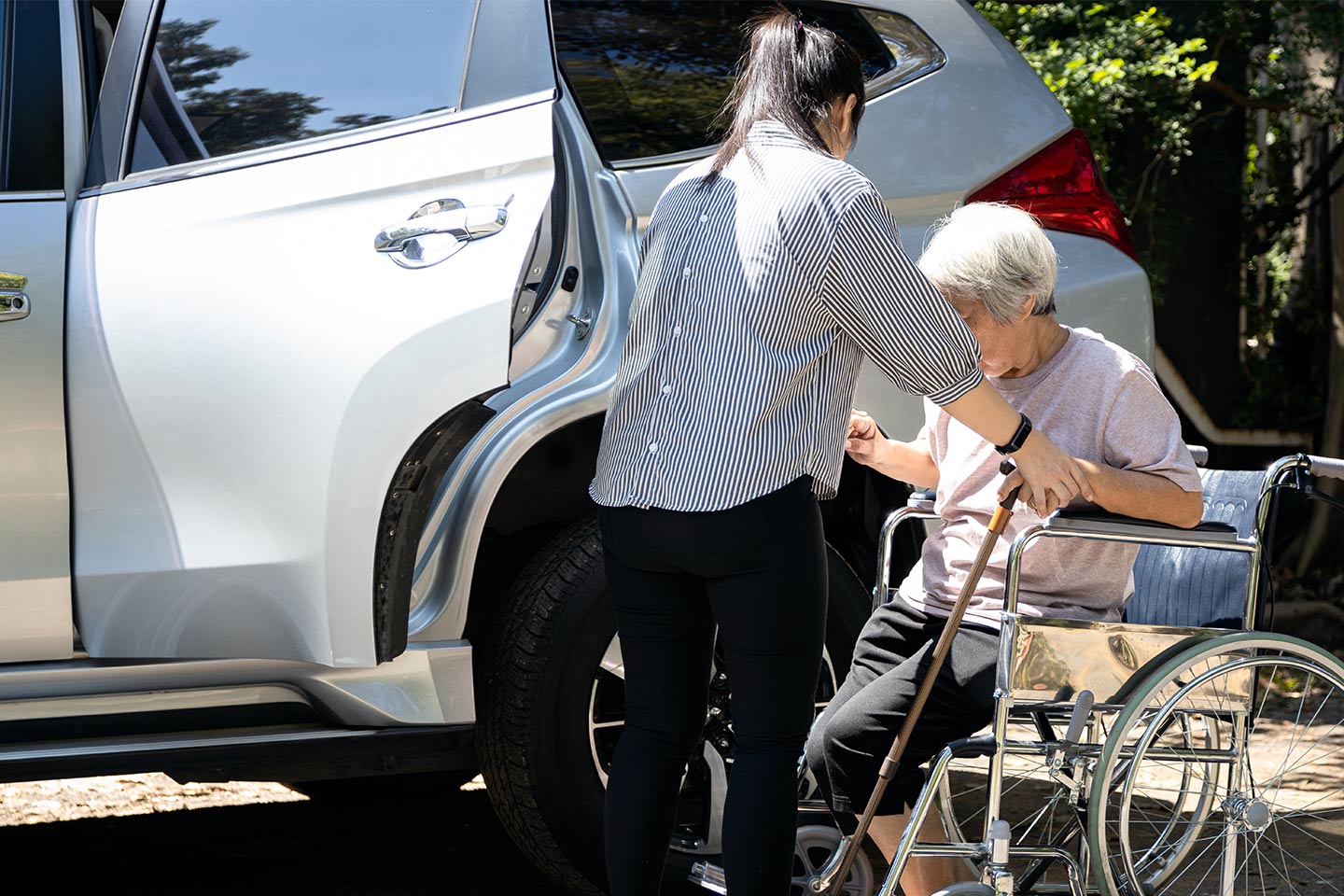 Photo of a person in a wheelchair being helped into a car
