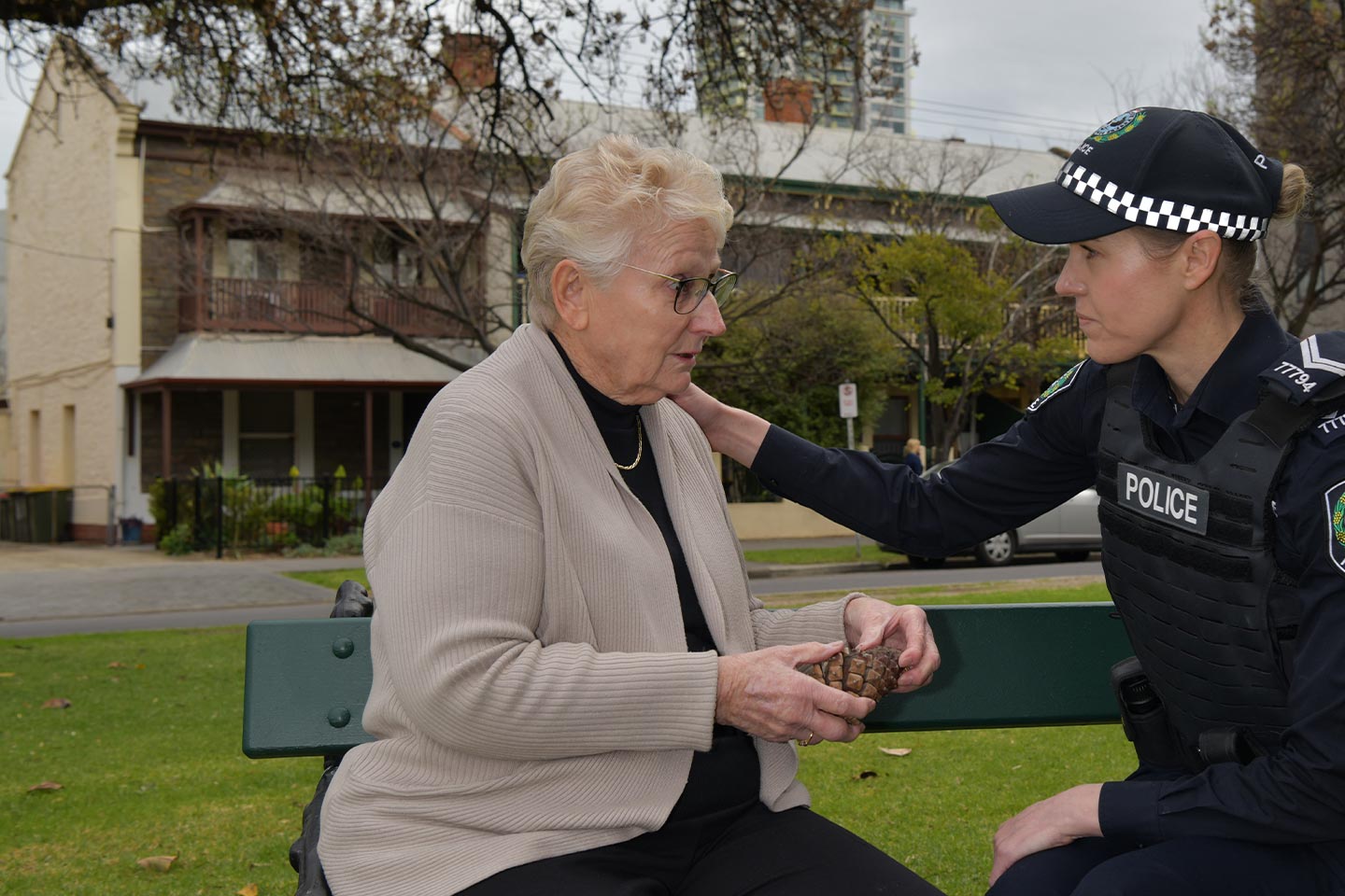 Photo of police officer comforting a woman on a park bench