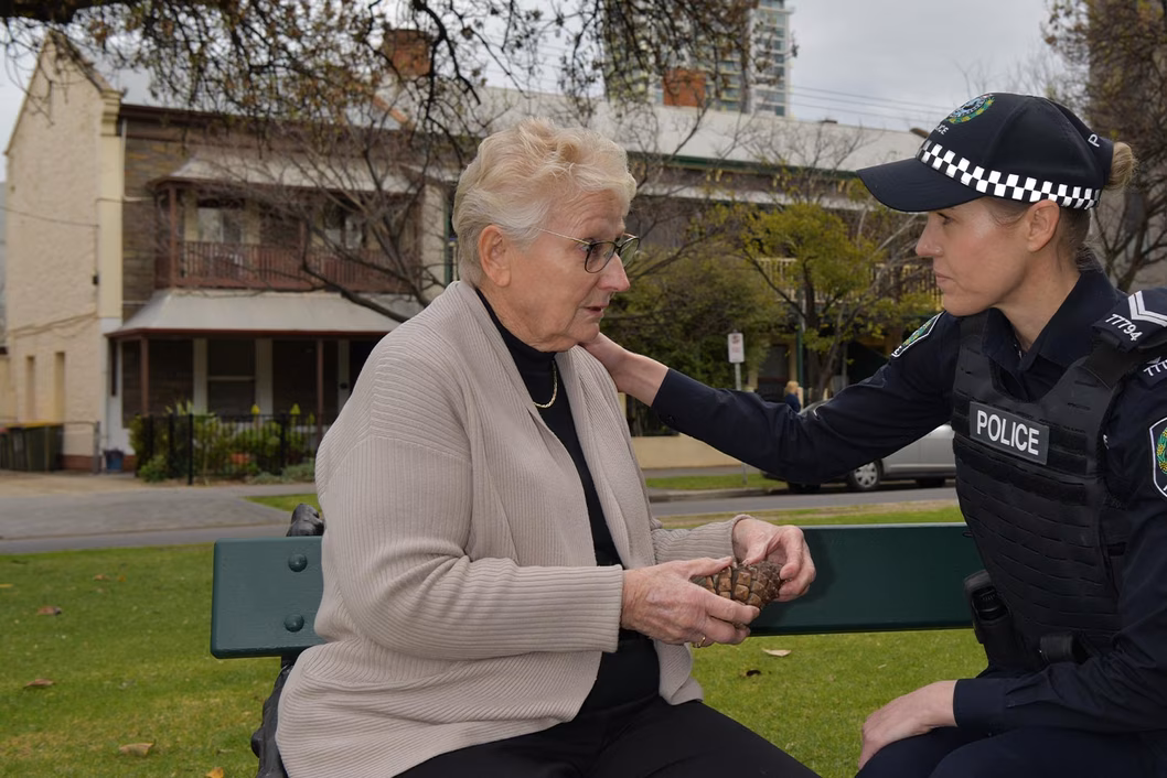Photo of police officer comforting a woman on a park bench
