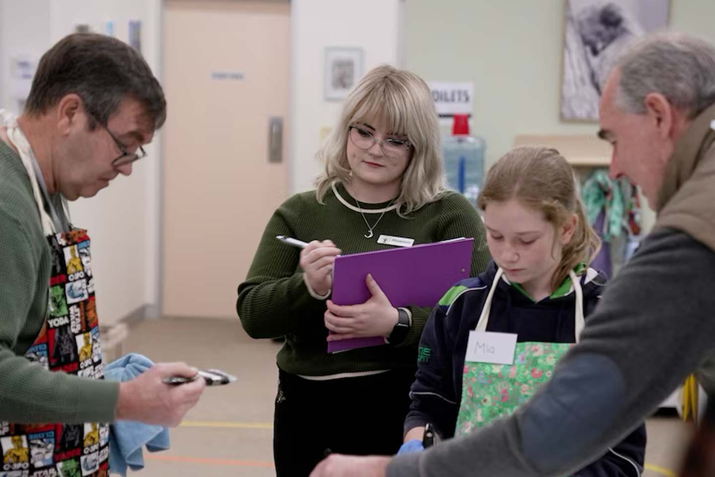 Photo of three generations of people wearing aprons