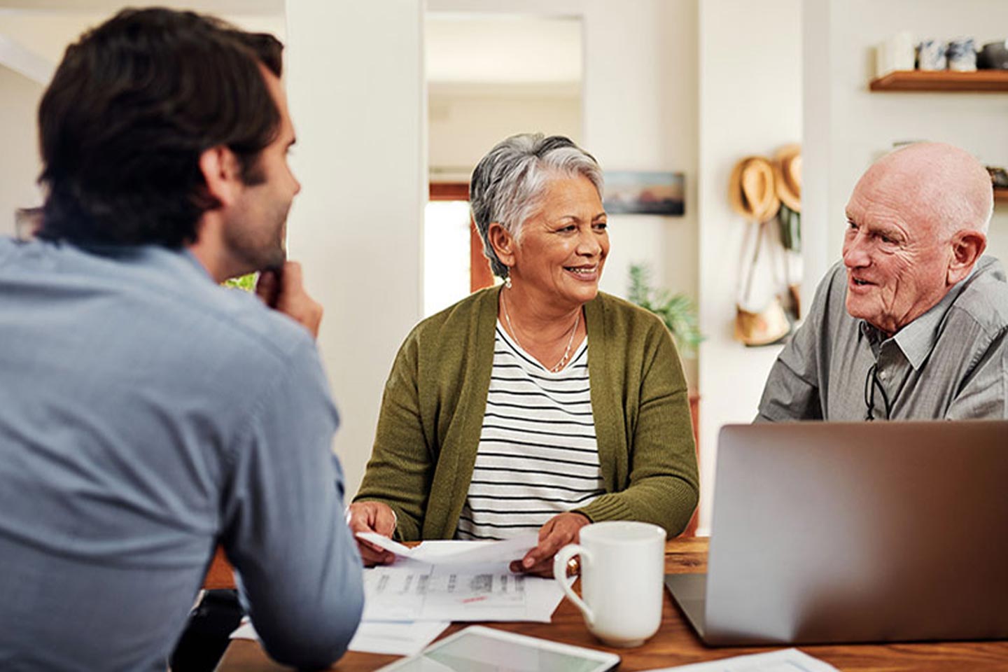 Photo of three people smiling and chatting with a laptop