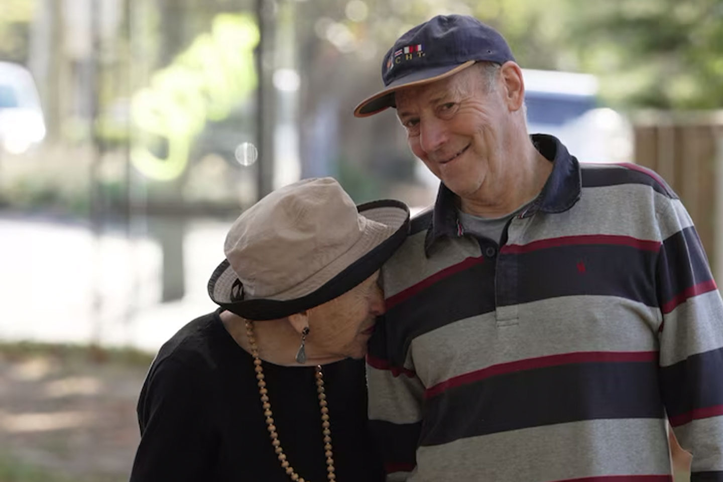 Photo of a woman with a hat and a man wearing a cap