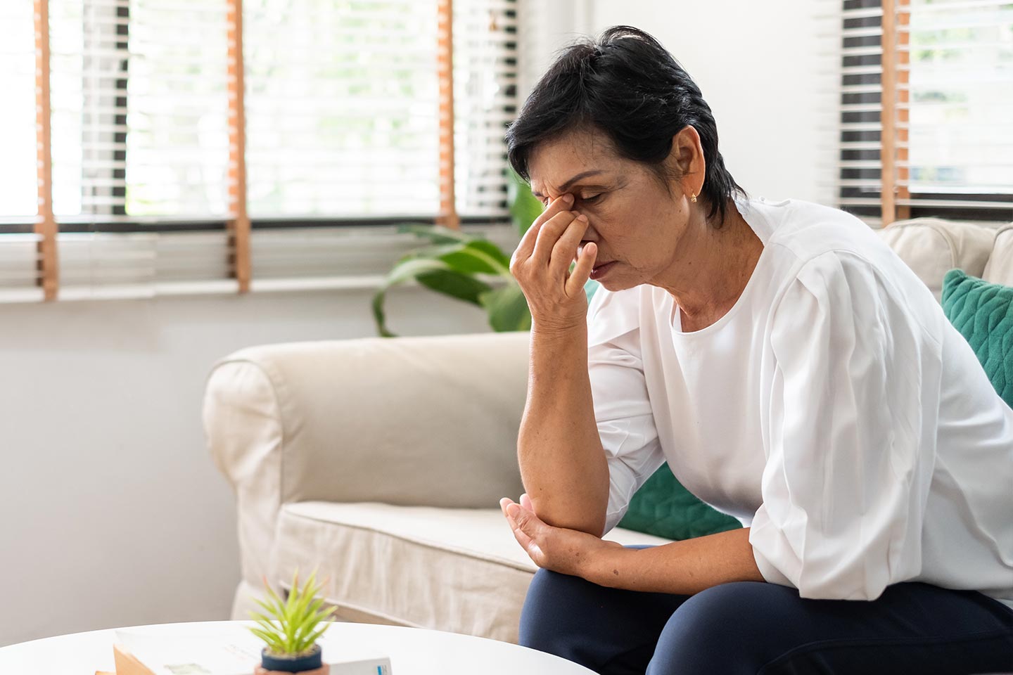 Photo of a seated woman pinching the bridge of her nose