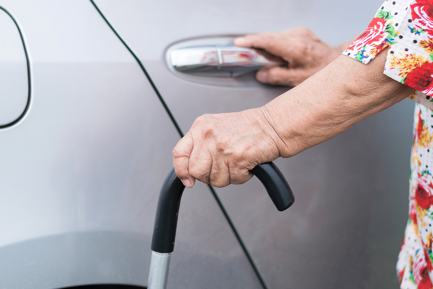 Image of an older woman with a walking stick opening a car door