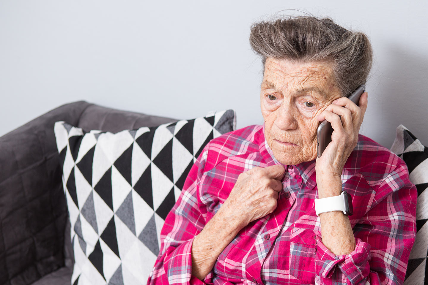 Photo of person on a mobile phone wearing a fuchsia plaid shirt