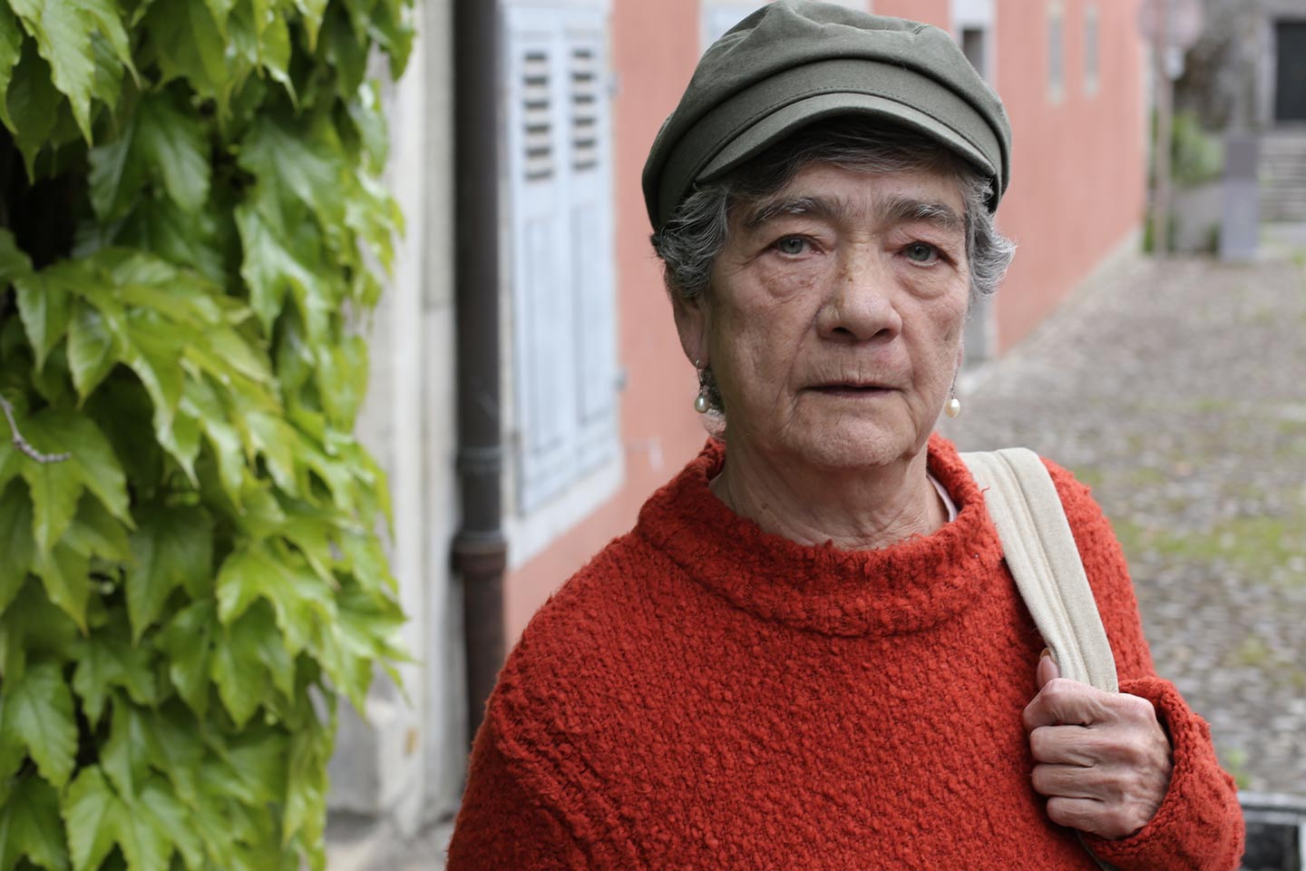 Photo of woman wearing an orange jumper and sage cap