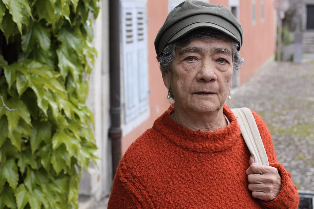Photo of woman wearing an orange jumper and sage cap