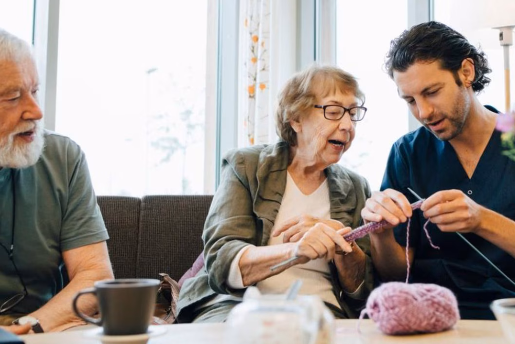 Photo of a woman showing a man how to knit