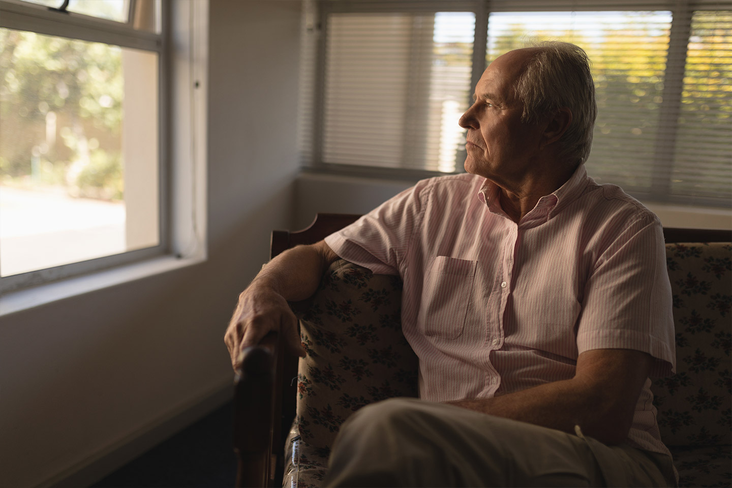 Photo of a seated man in a pale pink shirt