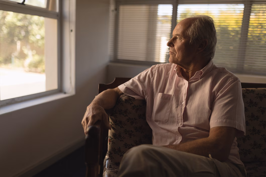 Photo of a seated man in a pale pink shirt