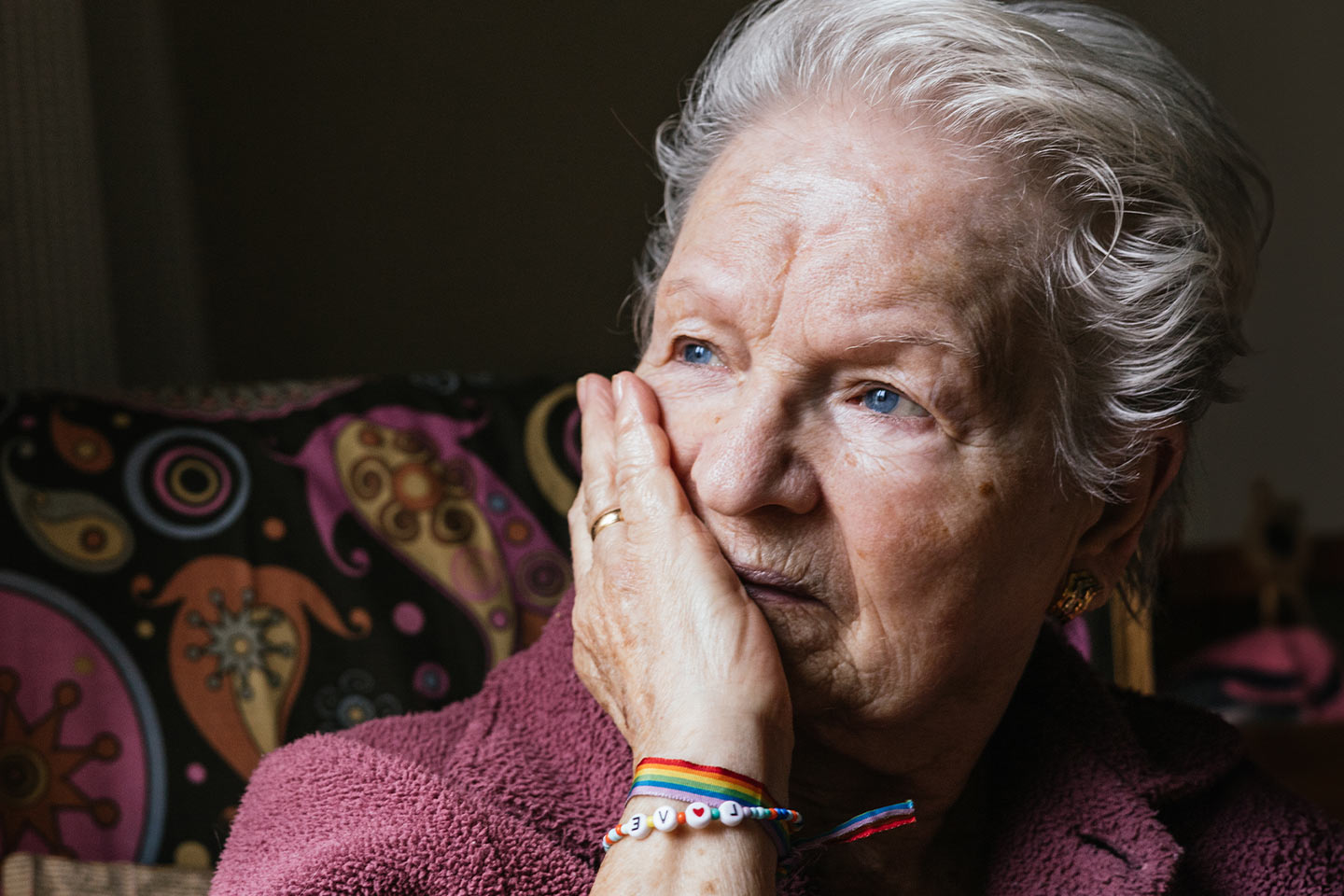 Image of an older woman with her hand at her face looking contemplative