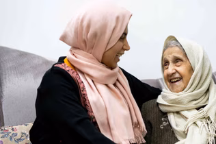 Photo of two women laughing and wearing headscarves