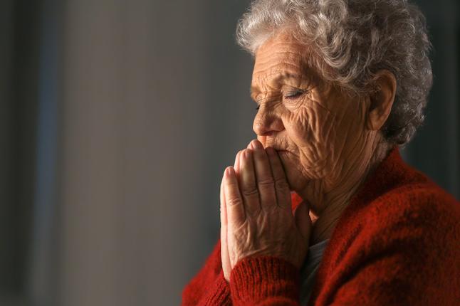 Photo of a woman praying in a red cardigan