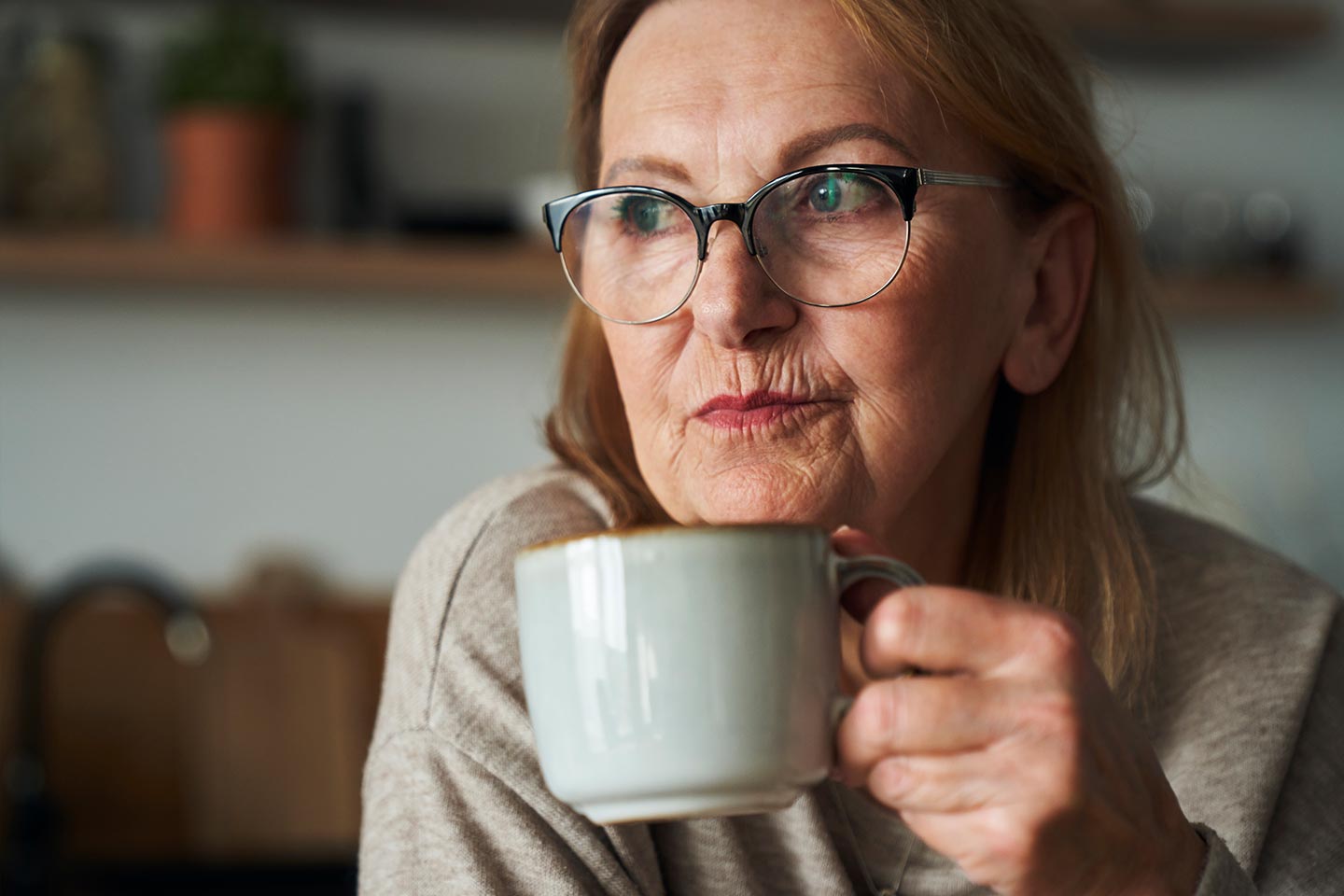 Photo of a woman holding a coffee cup and wearing glasses