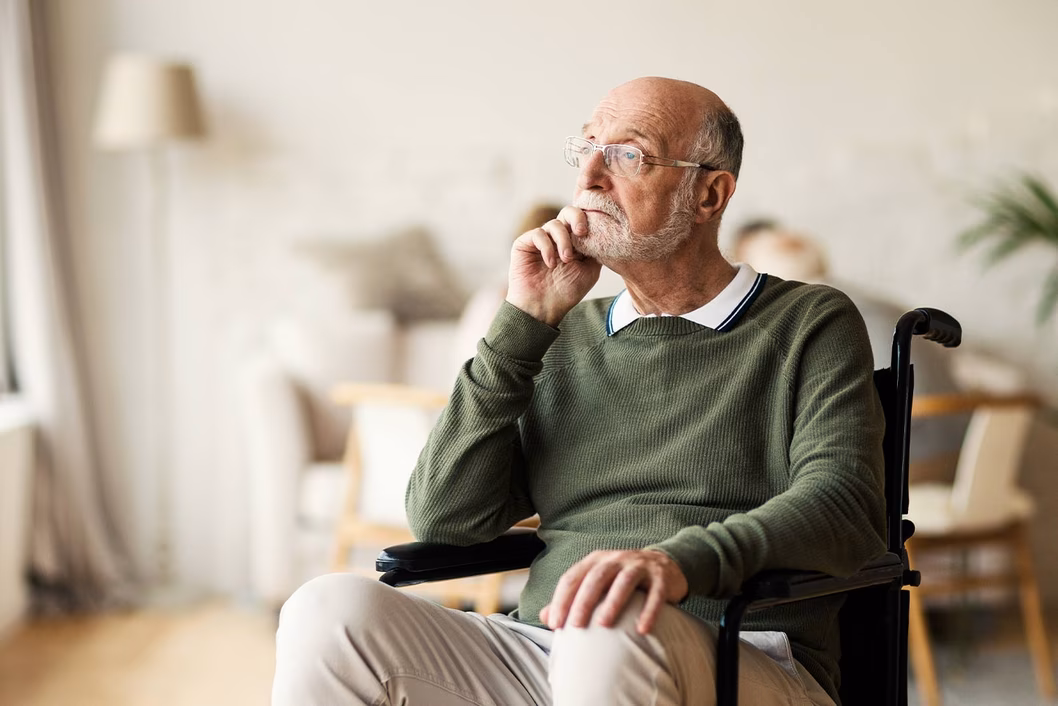 Photo of a seated man in a green jumper looking pensive