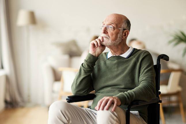 Photo of a seated man in a green jumper looking pensive