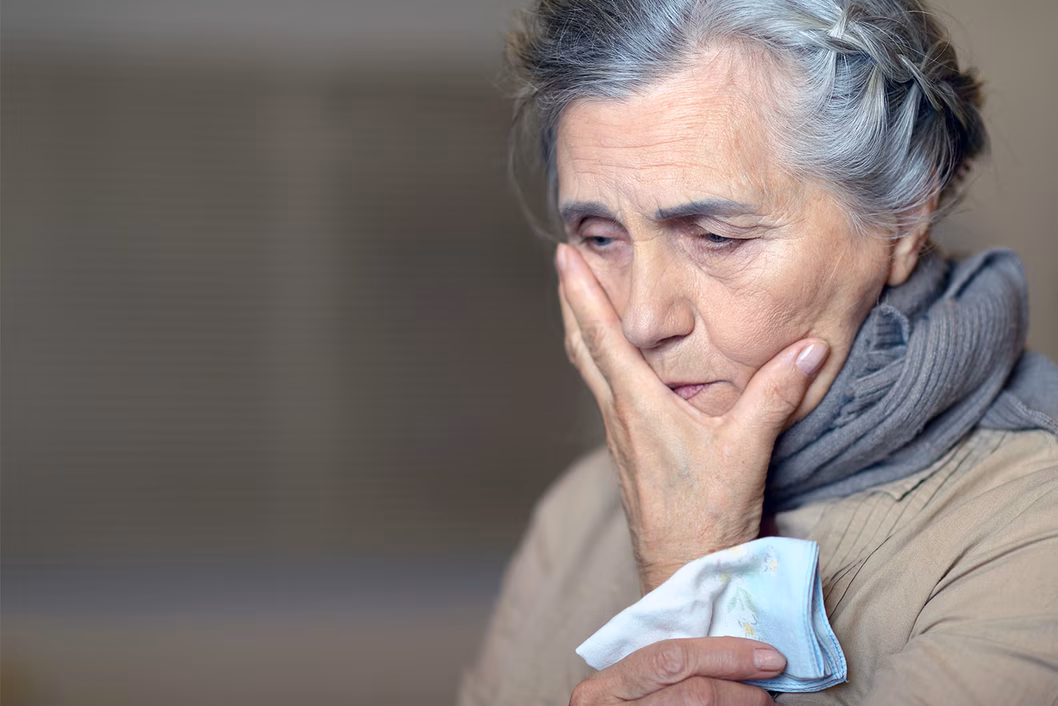 Photo of a woman with a hankie and her hand over her mouth