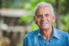 older man in a blue shirt looking directly to camera